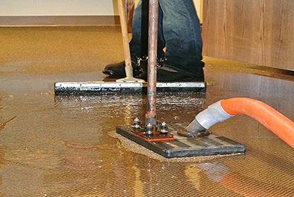 Dalworth technician using a water claw to extract water from flooring